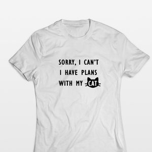 May include: White t-shirt with black text that reads "Sorry, I can't I have plans with my cat" and a black cat silhouette.