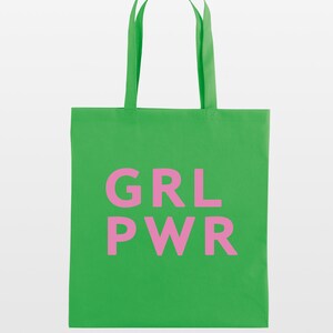 May include: A bright green tote bag with the pink text "GRL PWR" printed on the front. The bag has matching green handles and is made of a sturdy fabric, perfect for carrying groceries or other items.