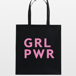 May include: Black tote bag with the pink text "GRL PWR". The bag has two black handles and is made of a sturdy material. The design is simple and bold, making it a statement piece.