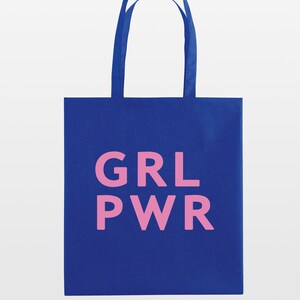 May include: A blue tote bag with pink text that reads "GRL PWR". The bag has two blue handles and is made of a sturdy fabric. The design is simple and bold, perfect for carrying books, groceries, or other items.