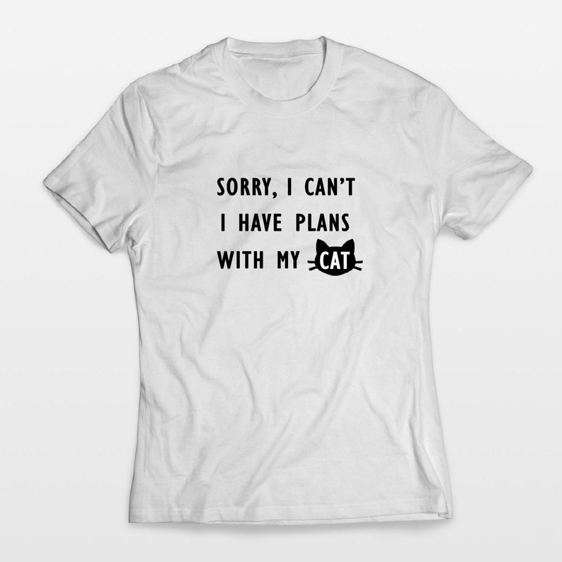 May include: White t-shirt with black text that reads "Sorry, I can't I have plans with my cat" and a black cat silhouette.