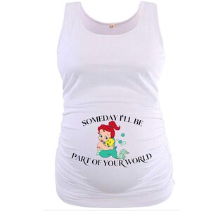 Op de afbeelding: Witte zwangerschapstanktop met een gerimpeld zijontwerp. De voorkant heeft een cartoonafbeelding van een zeemeermin met rood haar en een gele vis, samen met de tekst "Someday I'll Be Part of Your World."