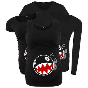 May include: Black maternity shirts with a cartoon Chain Chomp design. The image shows a short-sleeve tee, a tank top, a long-sleeve shirt, and a V-neck shirt. The Chain Chomp has a white face, red teeth, and a gray chain.