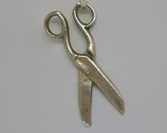 Op de afbeelding: Een zilveren ketting met een hanger in de vorm van een schaar. De schaar is open en de hanger is bevestigd aan een zilveren ketting.