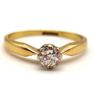 May include: A gold band engagement ring with a single round diamond.