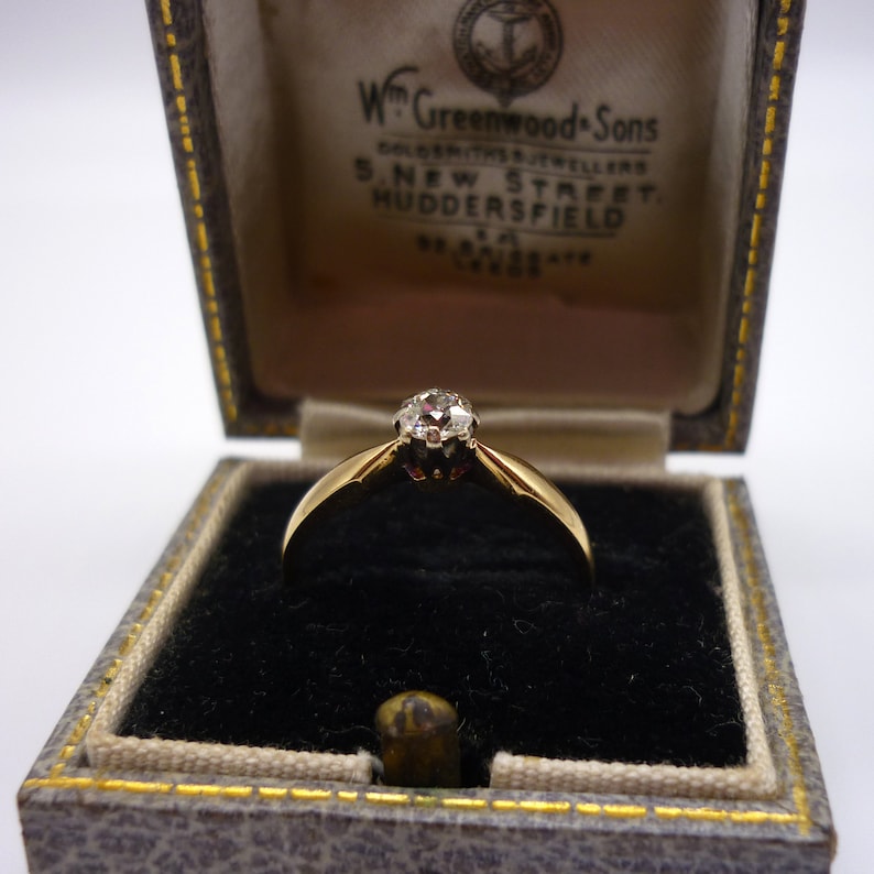May include: A gold ring with a single diamond in a black velvet ring box. The box is labeled "Wm Greenwood & Sons, Goldsmiths & Jewellers, S. New Street, Huddersfield."