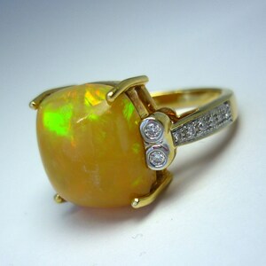 May include: A gold ring with a large, yellow opal gemstone and small diamonds set in the band.