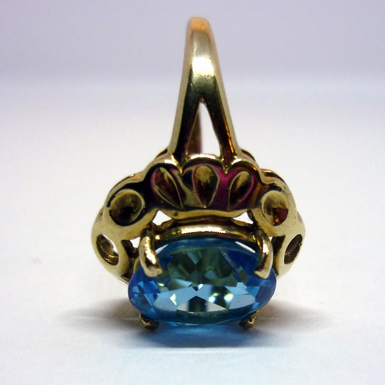 May include: A gold ring with a blue oval gemstone set in a delicate, ornate design.