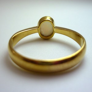 May include: A gold ring with a white opal gemstone. The ring is simple and elegant.