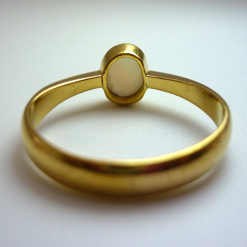 May include: A gold ring with a white opal gemstone. The ring is simple and elegant.