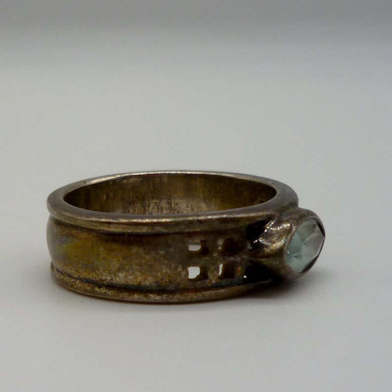 May include: A silver ring with a light blue gemstone set in a decorative band.