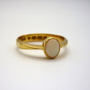 May include: A gold ring with a white opal gemstone. The ring is simple and elegant.