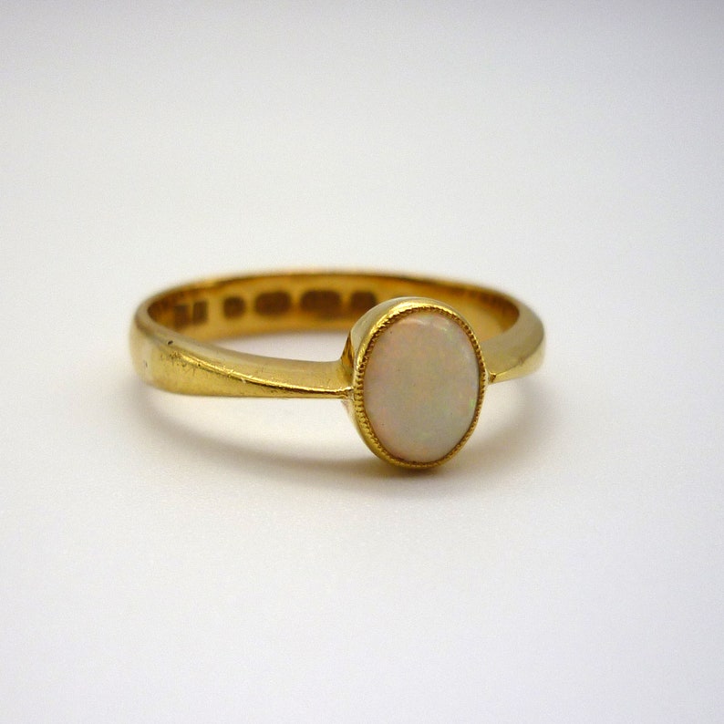 May include: A gold ring with a white opal gemstone. The ring is simple and elegant.