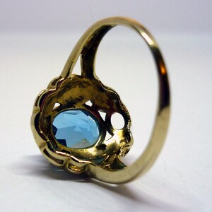May include: A gold ring with a light blue oval-shaped gemstone set in a filigree design.