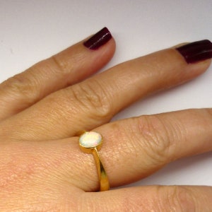 May include: A gold ring with a white opal gemstone. The ring has a simple, delicate design.