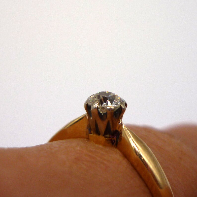 May include: A gold ring with a single, clear diamond set in a prong setting.