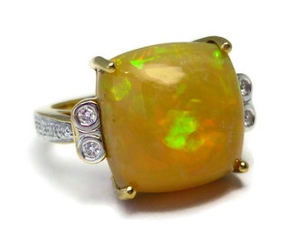 May include: A gold ring with a large, yellow opal gemstone and two smaller diamonds on the band.
