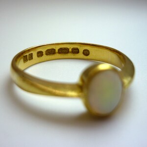 May include: A gold ring with a white opal gemstone. The inside of the band is stamped with "9ct 22 G 5".
