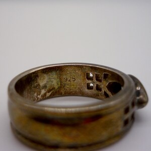 May include: A silver ring with a geometric design and the number "925" stamped on the inside.