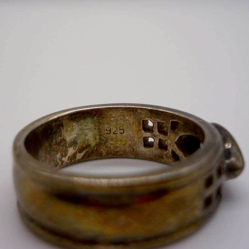 May include: A silver ring with a geometric design and the number "925" stamped on the inside.