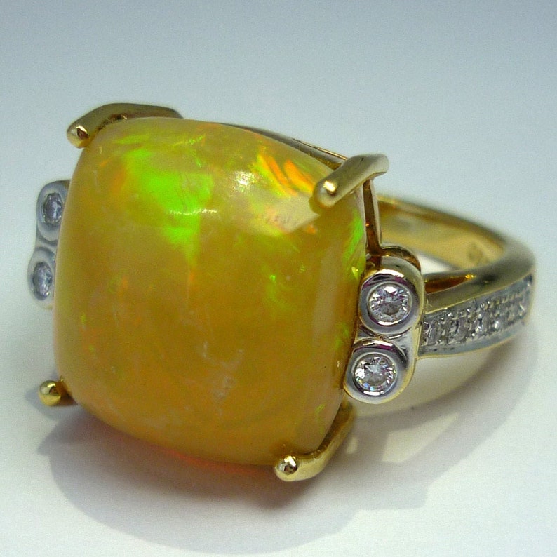 May include: A gold ring with a large, yellow opal gemstone and smaller diamonds set in the band.