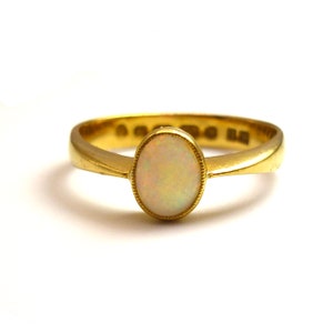 May include: A gold ring with an oval-shaped opal gemstone.