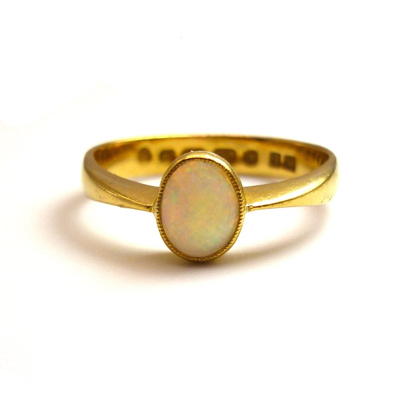 May include: A gold ring with an oval-shaped opal gemstone.