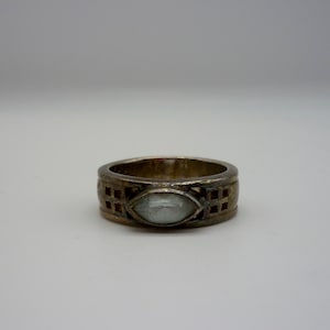 May include: A silver ring with a clear, faceted gemstone set in a geometric design.