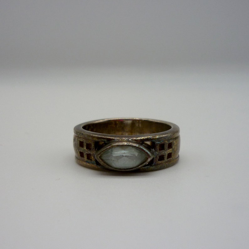 May include: A silver ring with a clear, faceted gemstone set in a geometric design.