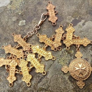 May include: A gold chain with multiple charms, each featuring a year from 1904 to 1930. The chain also includes a larger charm with the words "St. John Ambulance Assoc."