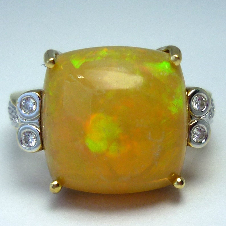 May include: A gold ring with a large, yellow opal gemstone and smaller diamonds on the sides.