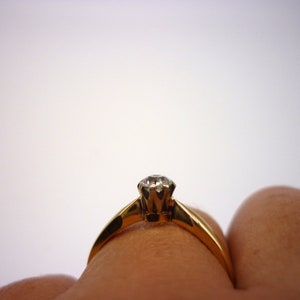 May include: A gold ring with a single diamond set in a prong setting.