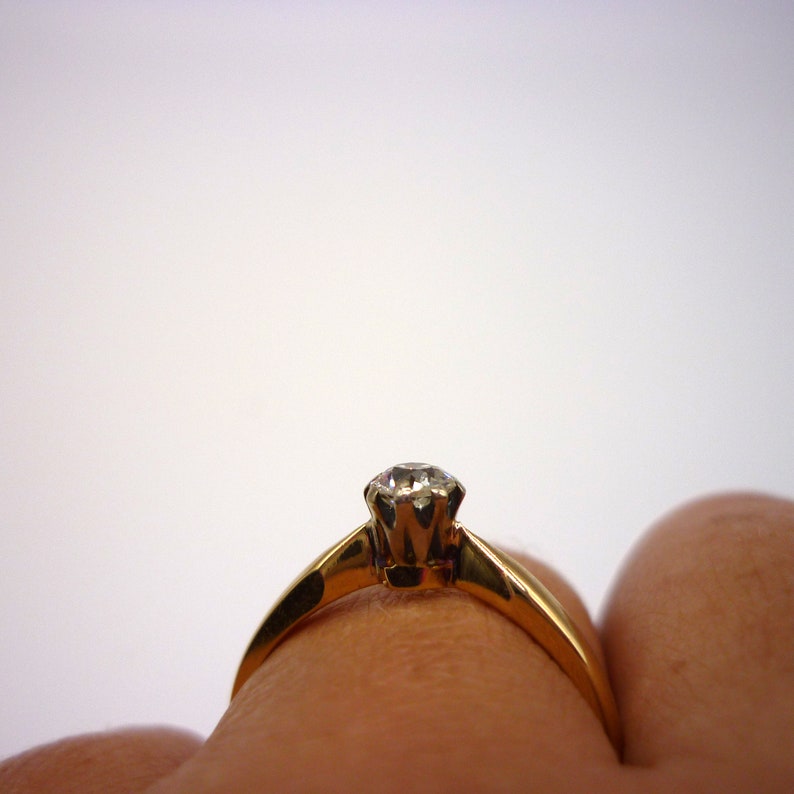 May include: A gold ring with a single diamond set in a prong setting.