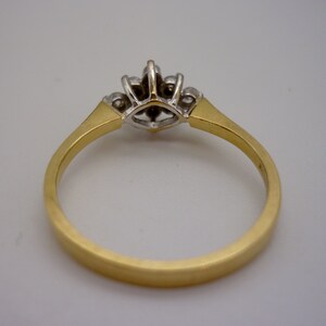 May include: A gold ring with a cluster of small diamonds. The ring features a gold band and a central setting with multiple small diamonds. The diamonds are set in a silver-colored metal, and the band has a brushed finish.