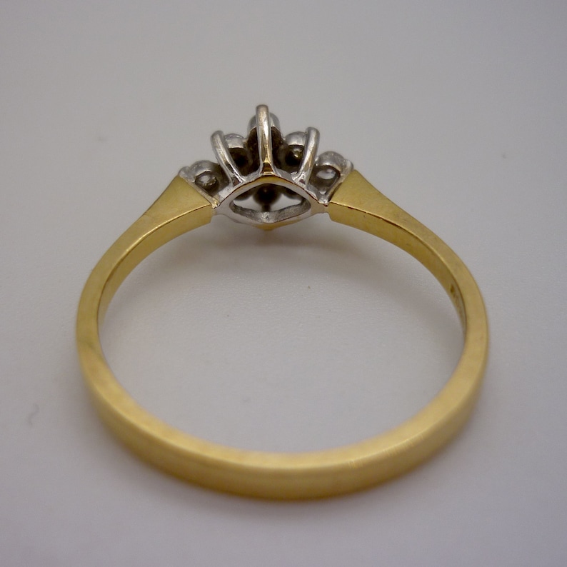May include: A gold ring with a cluster of small diamonds. The ring features a gold band and a central setting with multiple small diamonds. The diamonds are set in a silver-colored metal, and the band has a brushed finish.