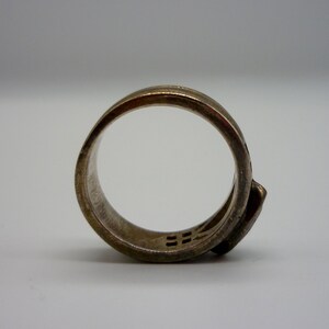 May include: A silver ring with a unique design featuring a geometric pattern. The ring is made of a smooth, polished metal and has a simple, modern style.