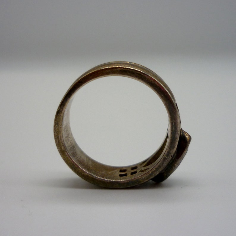 May include: A silver ring with a unique design featuring a geometric pattern. The ring is made of a smooth, polished metal and has a simple, modern style.