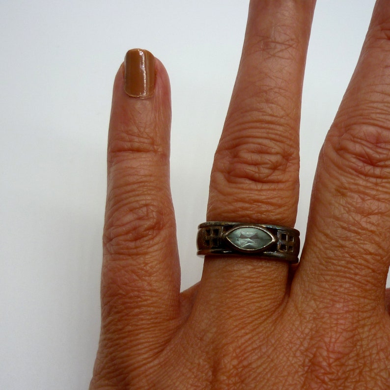 May include: A silver ring with a light blue gemstone set in a geometric design.