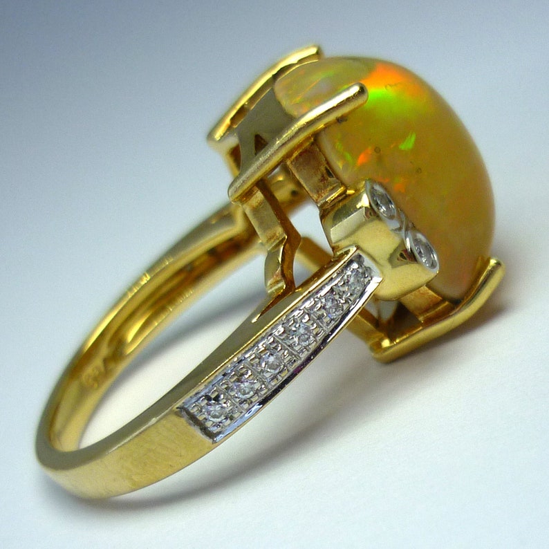 May include: A gold ring with a large opal gemstone and smaller diamonds set in the band.