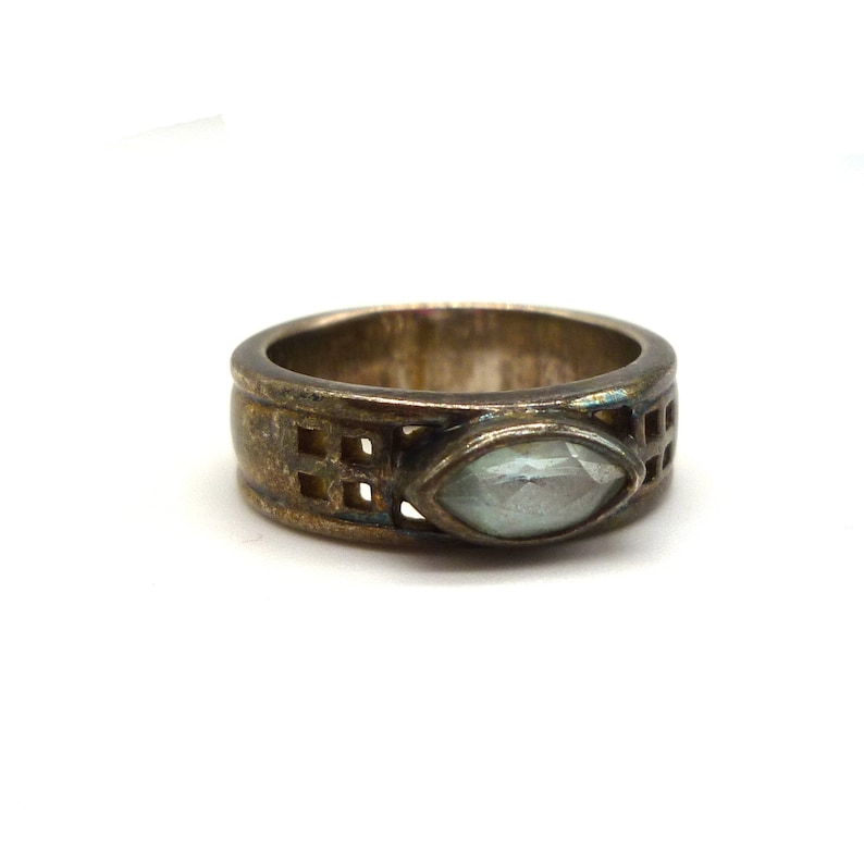 May include: A silver ring with a clear, faceted gemstone set in a geometric design.