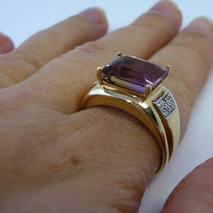 May include: A gold ring featuring a large, rectangular, purple amethyst gemstone and a smaller band of diamonds set in gold.