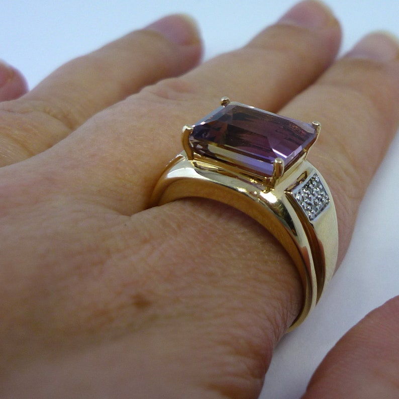 May include: A gold ring featuring a large, rectangular, purple amethyst gemstone and a smaller band of diamonds set in gold.