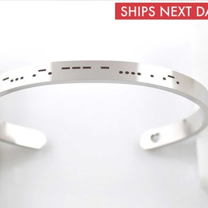 May include: A silver bangle bracelet with a heart charm and a message in Morse code.
