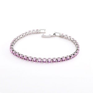 Puede incluir: Un brazalete de tenis plateado con piedras de circonita cúbica rosas.