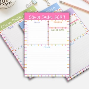 May include: A stack of colorful notepads with a grid border. The top notepad is pink with the name "Olivia Smith, BCBA" and sections for "to do", "priority", "call or email", and "notes". Other notepads are green, blue, and purple.