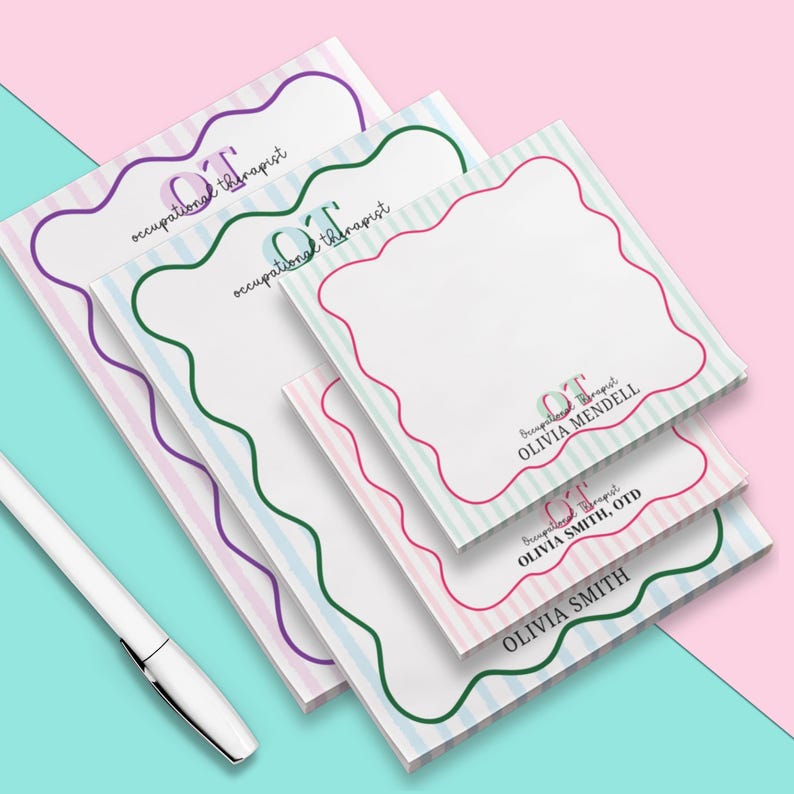 May include: A stack of notepads with a wavy border design in purple, green, and pink. The notepads have a striped background and the text "OT occupational therapist" is printed on the top notepad. The bottom notepad has the text "OLIVIA SMITH, OTD". A white pen is in the image.