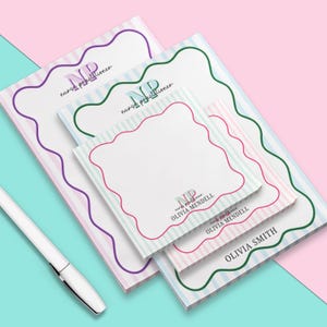 May include: A set of four notepad sets with a striped design and a wavy border. The notepads feature the text "nurse practitioner" and the initials "NP" in a colorful font. The notepads are personalized with the names "Olivia Smith", "Olivia Mendelll", and "Olivia Mendelll".