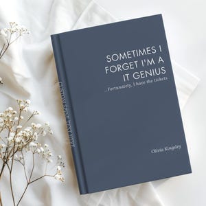 May include: A dark blue hardcover book with white text that reads SOMETIMES I FORGET I'M A IT GENIUS ...Fortunately, I have the tickets. The spine features the text CUSTOM SPINE TEXT HERE and the bottom right corner displays the name Olivia Kingsley.