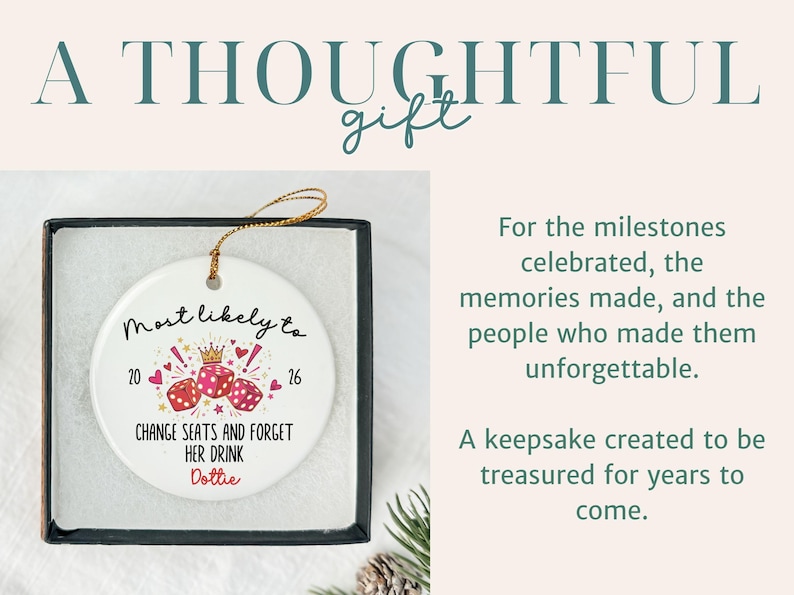 May include: A round white ceramic ornament with a gold hanging string, presented in a black box. The ornament features three red dice, a gold crown, and the text: Most likely to 20 16 CHANGE SEATS AND FORGET HER DRINK Dottie, surrounded by small hearts.