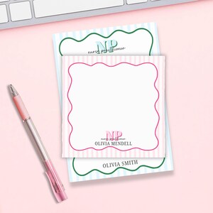May include: Two pink and blue striped notepads with a scalloped border. The top notepad has the text "NP nurse practitioner" in green and blue. The bottom notepad has the text "NP nurse practitioner OLIVIA MENDEL" in pink and green. The bottom notepad also has the text "OLIVIA SMITH" in green.